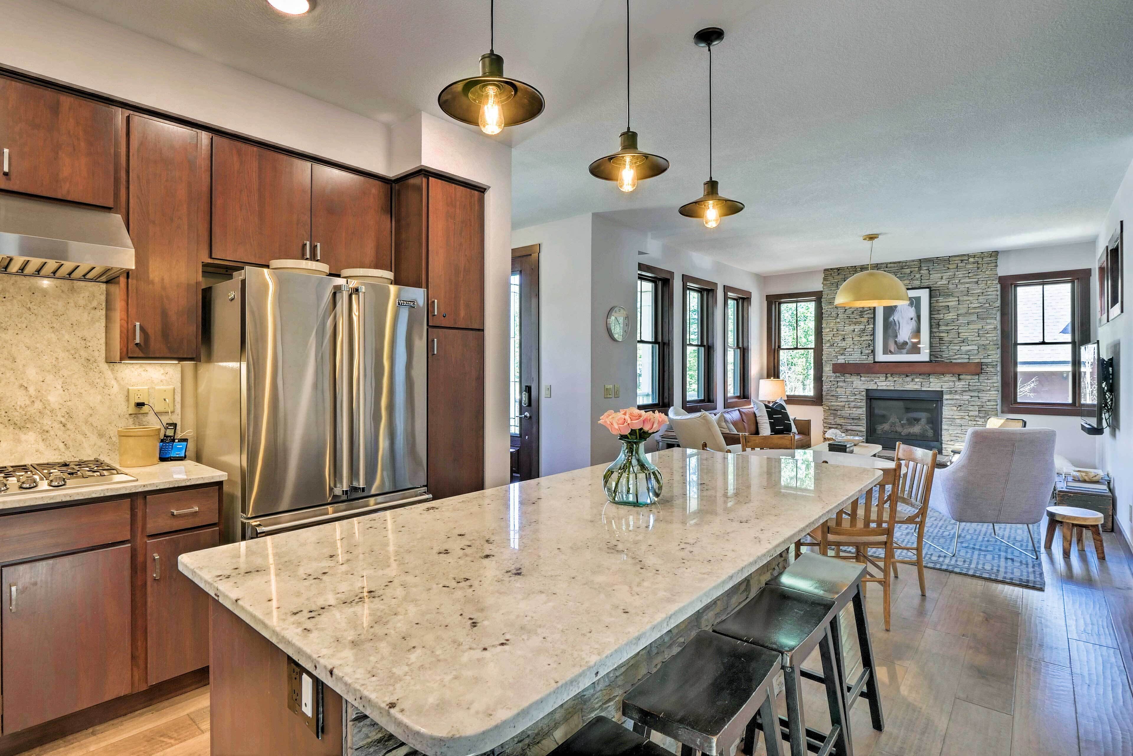 A modern kitchen with stainless steel appliances, a large island, and pendant lighting.