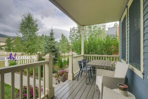 A wooden deck with a table and chairs, surrounded by a white fence and various plants.