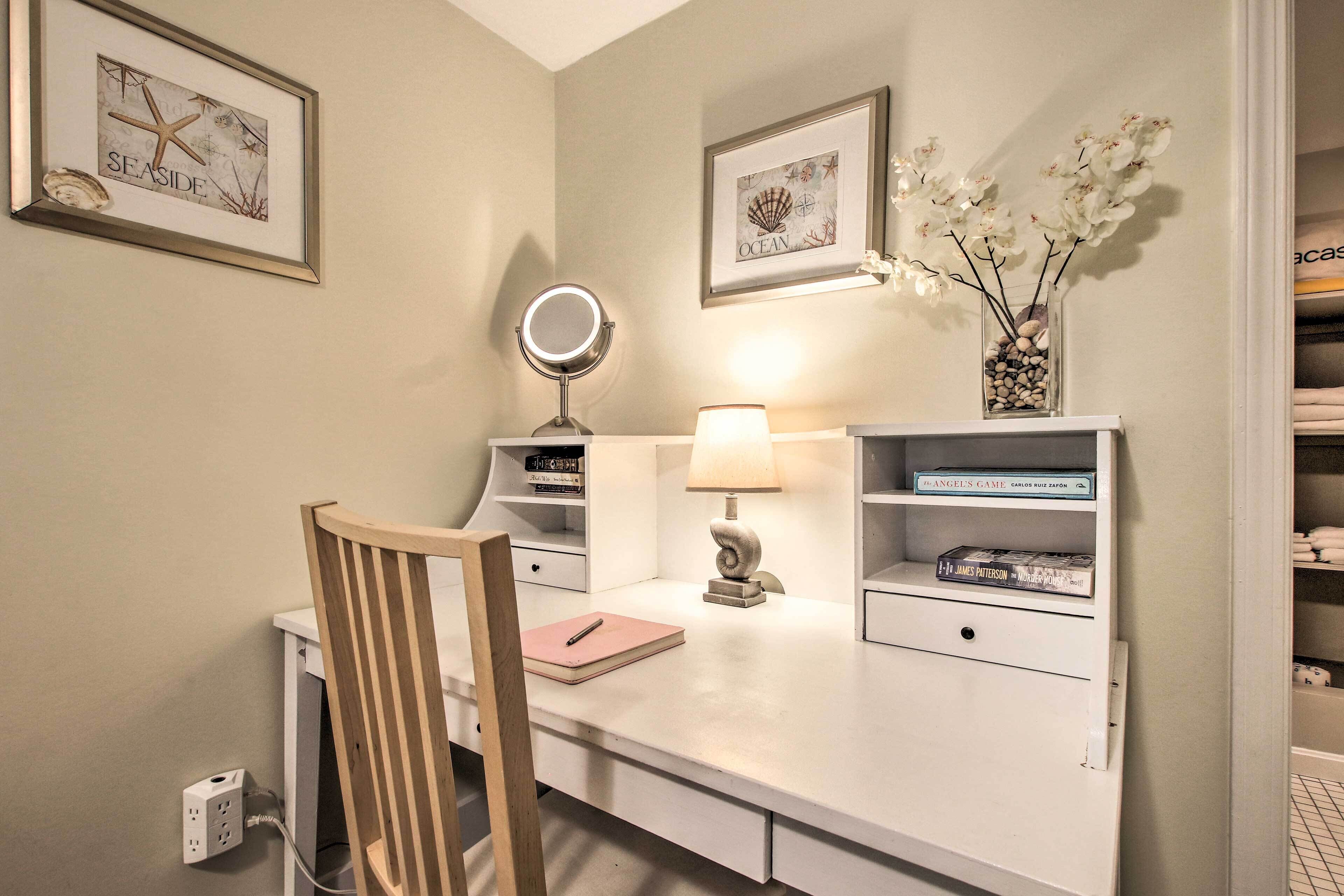 Un bureau bien rangé, avec une chaise, une lampe, un miroir et une étagère contenant des livres et des objets décoratifs.