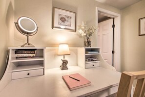 A neatly organized vanity area with a mirror, a lamp, and a shelf with books and decorative items. - Inviting Salem Apartment Near Waterfront & Museums (Salem)
