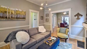 A living room with a gray sofa, a blue ottoman, and a painting on the wall. - Louisville Home w/ Hot Tub in The Highlands! (Louisville)