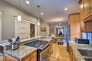 A modern kitchen with granite countertops, stainless steel appliances, and wooden cabinets. - Louisville Home w/ Hot Tub in The Highlands! (Louisville)