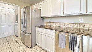 A kitchen with white cabinets, a stainless steel refrigerator, a tiled backsplash, and a countertop with towels. - Fayetteville Home w/ Hot Tub ~ 3 Mi to U of A! (Fayetteville)