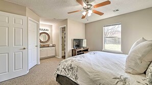 A bedroom with a bed, a ceiling fan, a TV, a window, and a door. - Fayetteville Home w/ Hot Tub ~ 3 Mi to U of A! (Fayetteville)