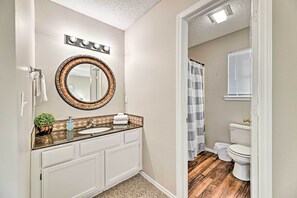 Baño con tocador, lavabo, espejo y perchero para toallas.