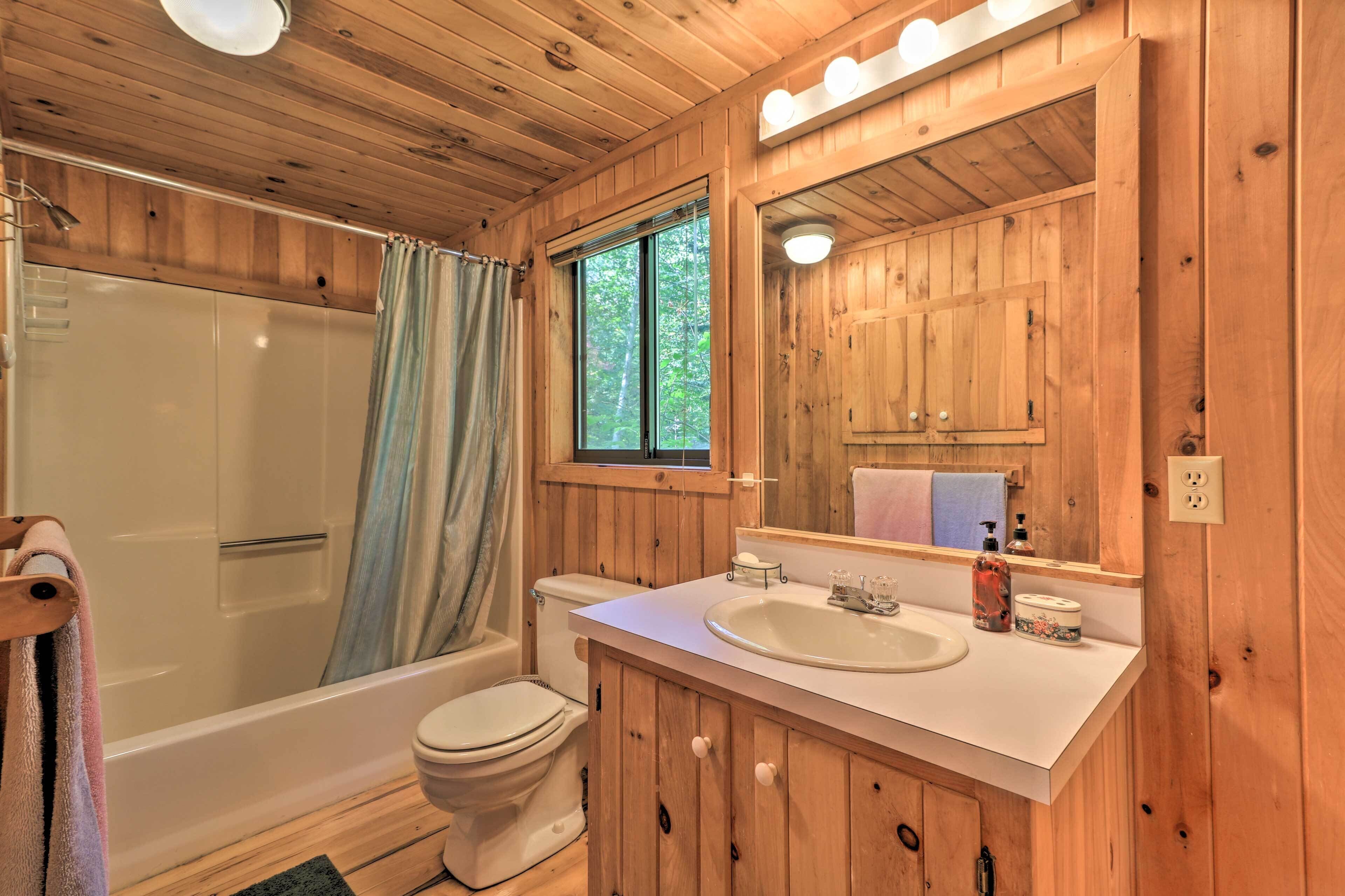 Ein Badezimmer einer Holzhütte mit Badewanne, Toilette und Waschbecken.