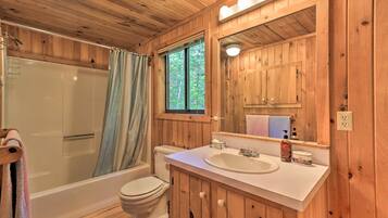 Ein Badezimmer einer Holzhütte mit Badewanne, Toilette und Waschbecken.