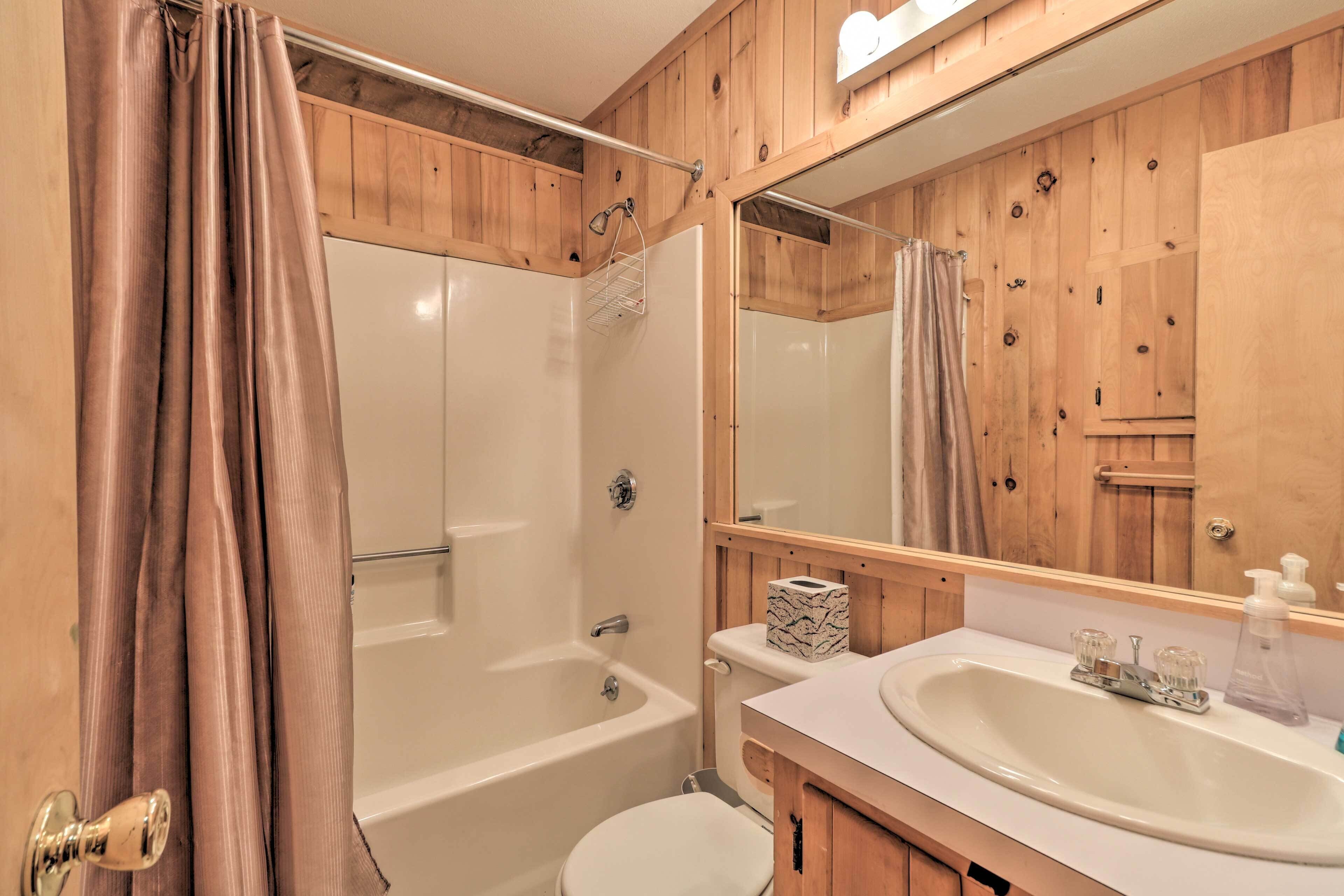 Un baño con tocador de madera, lavabo, inodoro y bañera.