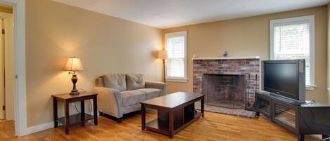 A living room with a sofa, a coffee table, a TV, and a fireplace.