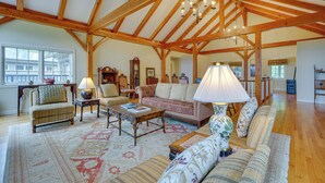 A spacious living room with wooden beams, a large window, and a cozy seating area with a patterned rug. - Luxury Vacation Rental in the Berkshires! (Williamstown)