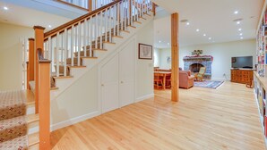 A spacious living area with a wooden staircase, a fireplace, and a television. - Luxury Vacation Rental in the Berkshires! (Williamstown)