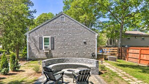 A house with a stone fireplace, two Adirondack chairs, and a wooden deck. - Cape Cod Escape ~ 2 Mi To Beaches & Dining! (South Yarmouth)