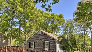 A single-story wooden house with a gabled roof, surrounded by a wooden fence and trees. - Cape Cod Escape ~ 2 Mi To Beaches & Dining! (South Yarmouth)