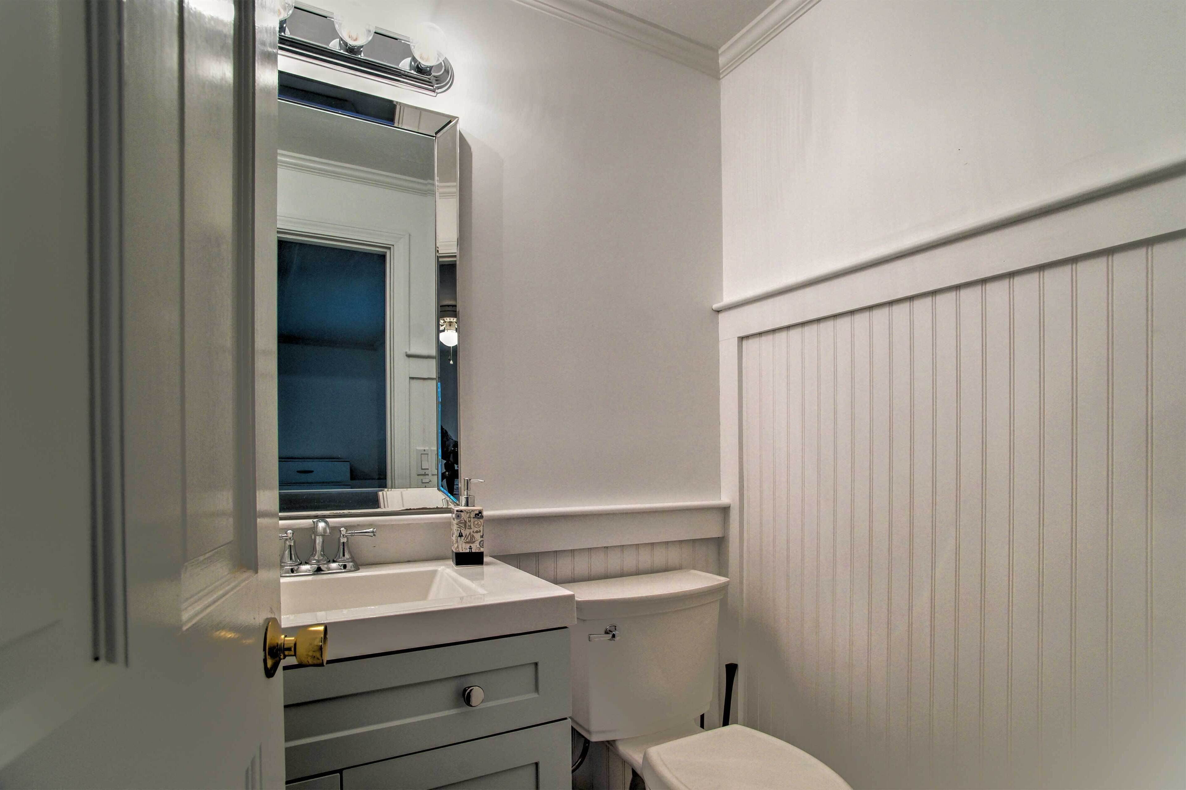 Une petite salle de bain avec un meuble-lavabo blanc, un miroir, des toilettes et une étagère fixée au mur.