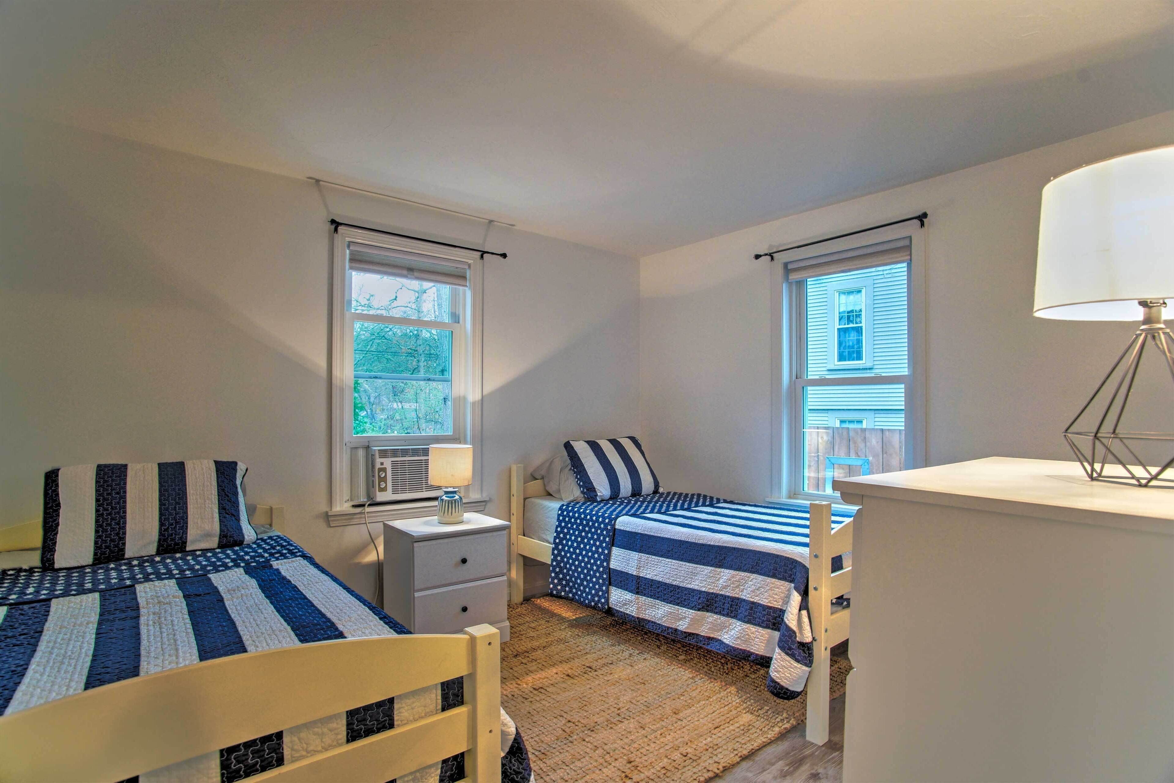 Une chambre avec deux lits, une table de chevet avec une lampe et une fenêtre avec des stores.
