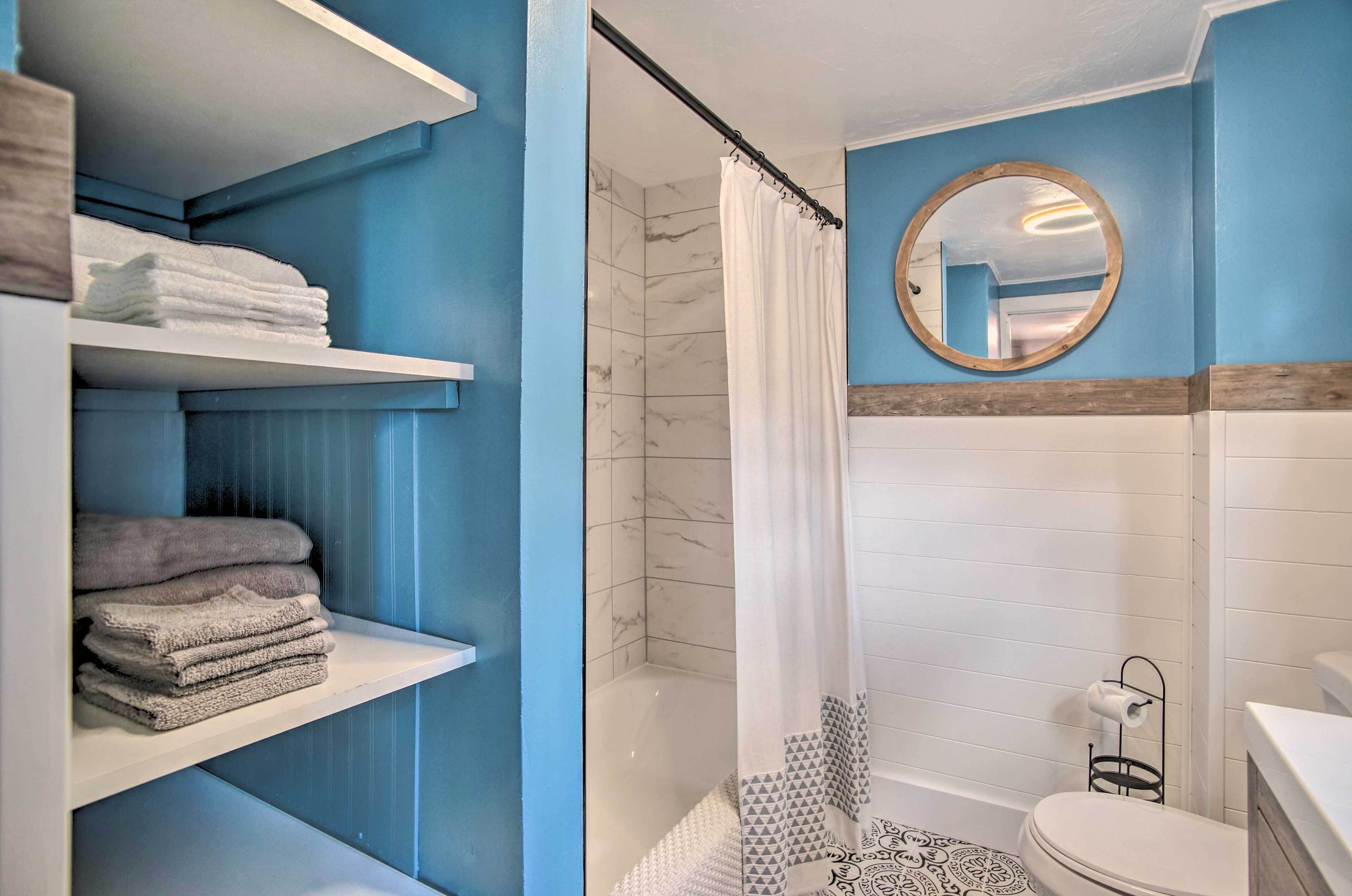 Ein Badezimmer mit Dusche, Toilette und Regalen mit Handtüchern.
