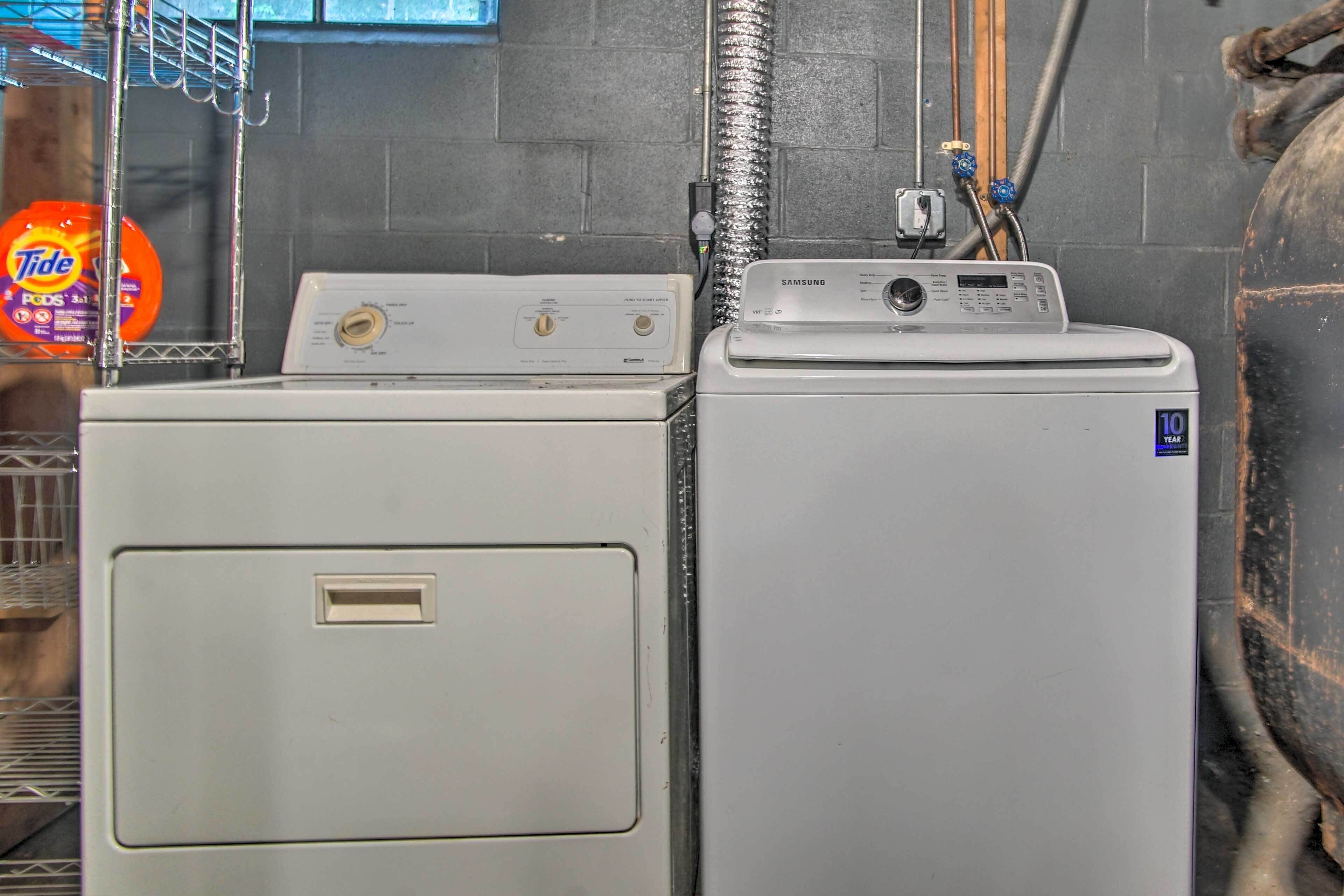 Un espace buanderie comprenant deux machines à laver et deux sèche-linge superposés, un distributeur de lessive et un chauffe-eau.