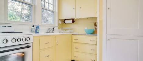 A kitchen with a white stove, yellow cabinets, and a window.