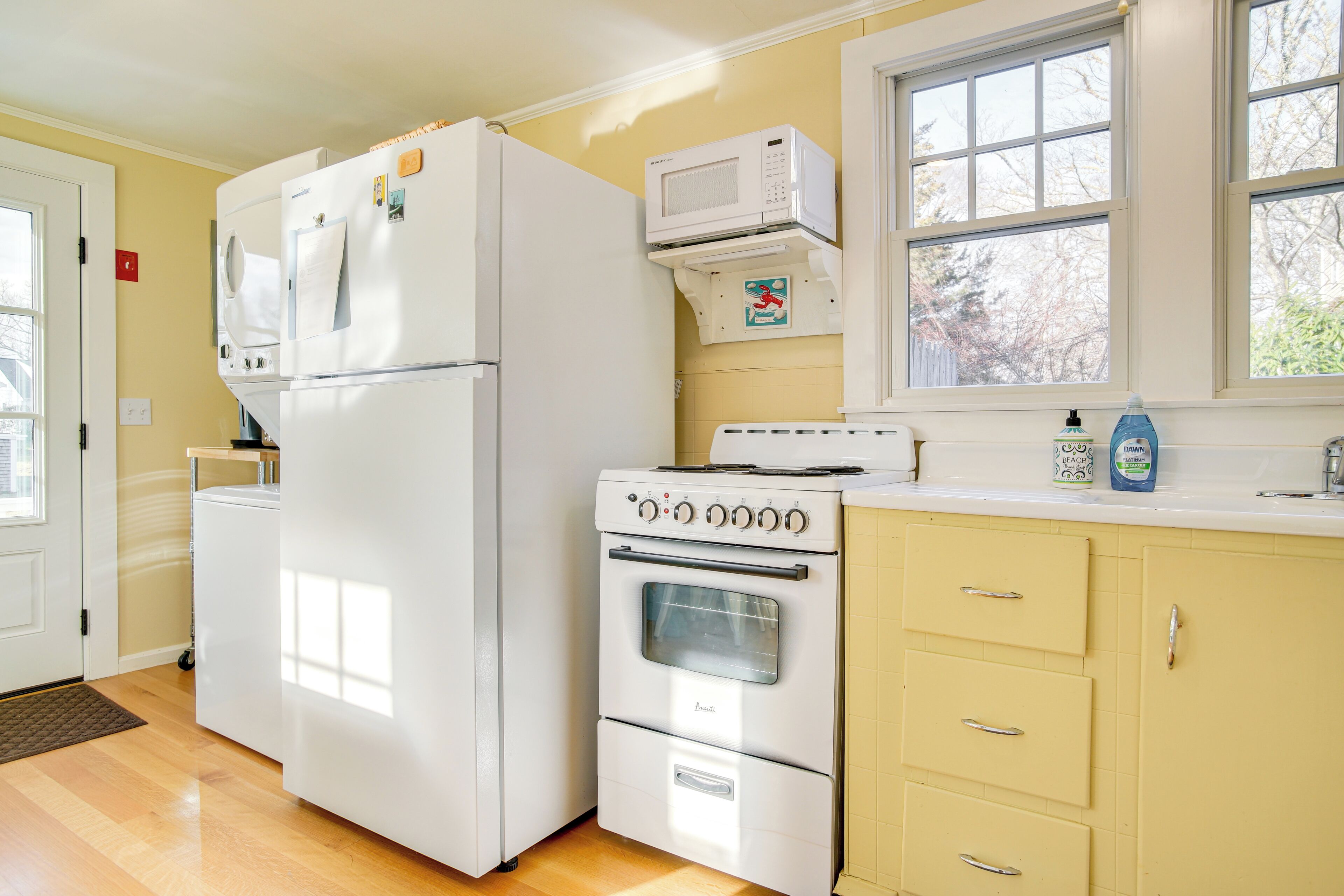 A kitchen with a refrigerator, oven, microwave, and yellow cabinets.