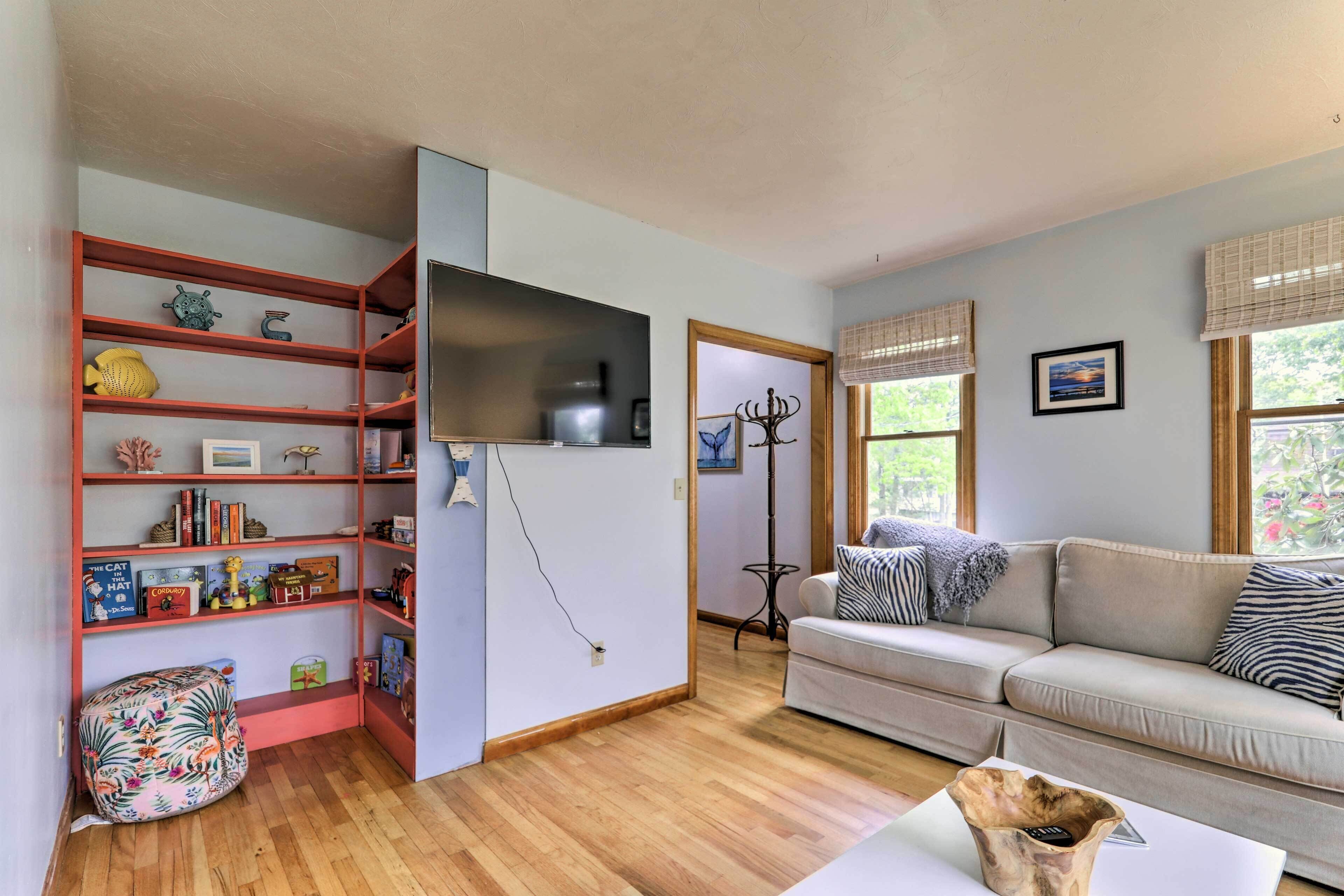 A living room with a sofa, a coffee table, a bookshelf, and a TV mounted on the wall.