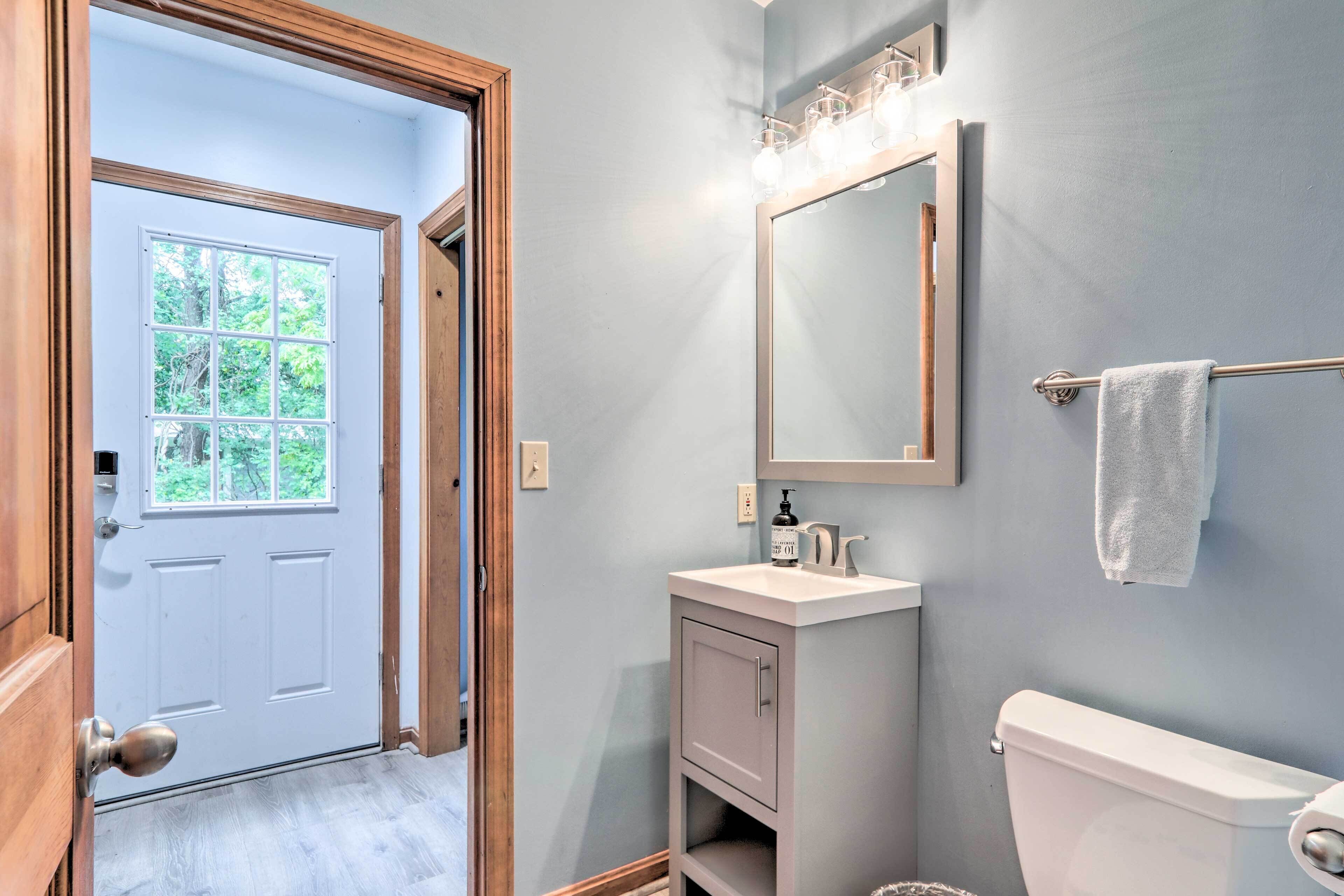 Une salle de bain avec des toilettes blanches, un lavabo avec un miroir au-dessus et un porte-serviettes avec une serviette.