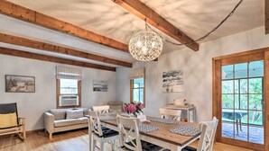 Een eetruimte met een houten tafel, witte stoelen en een hanglamp.