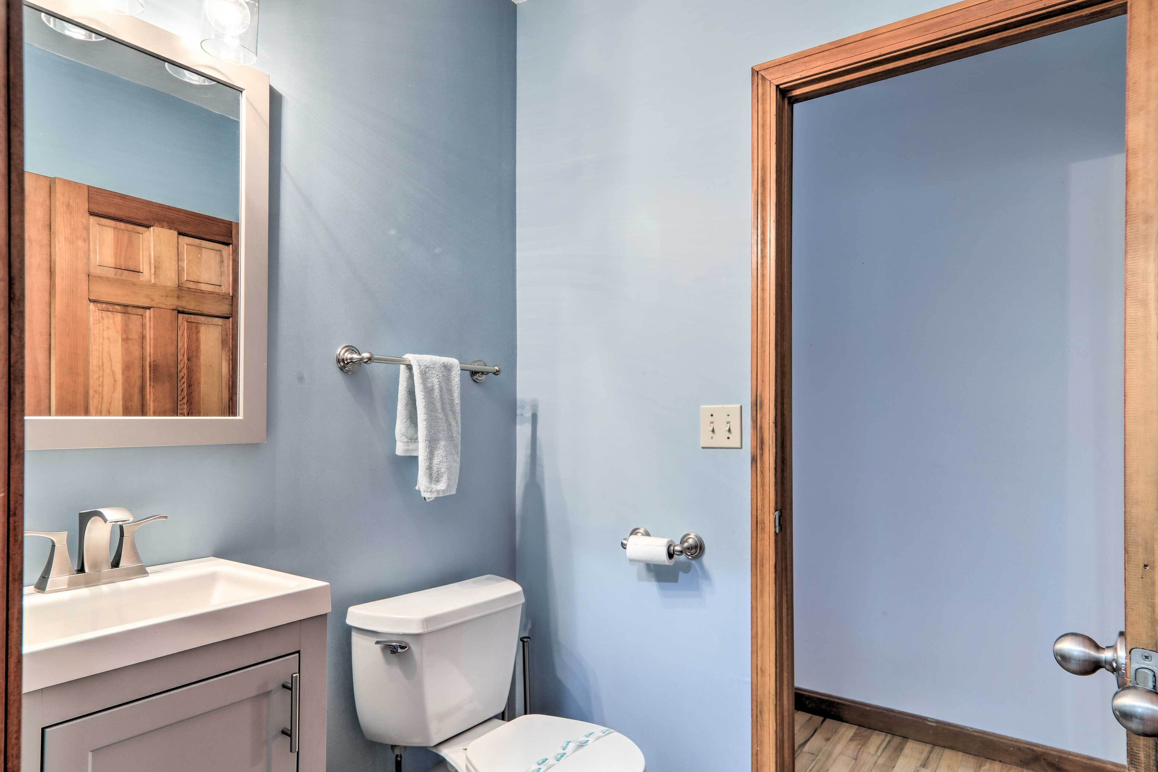 A bathroom with a wooden door, a white sink, a toilet, and a towel hanging on a rack.