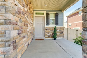 A house with a stone facade, a front door, a small porch, and a potted plant.