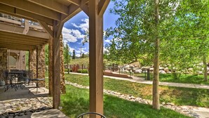A covered patio with outdoor seating, a stone wall, and a view of a landscaped area with trees and rocks. - 4 Mi to Breckenridge Resort: Condo w/ Sauna Access (Breckenridge)