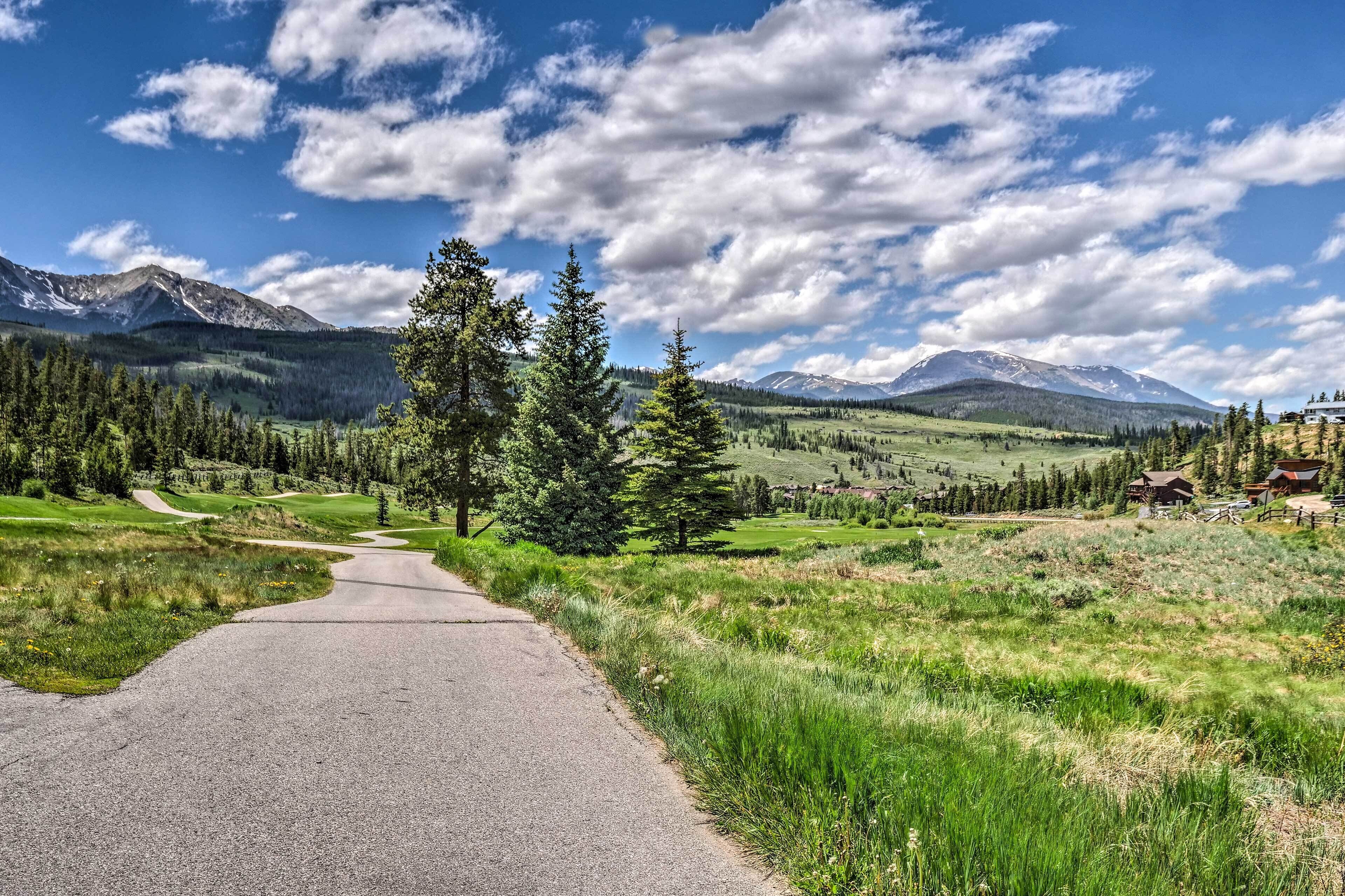 A paved road leading through a mountainous landscape with a clear sky and scattered clouds.