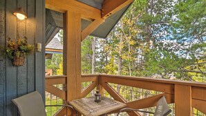 Eine Holzterrasse mit Korbstühlen und einem Tisch, mit Blick auf ein bewaldetes Gebiet.