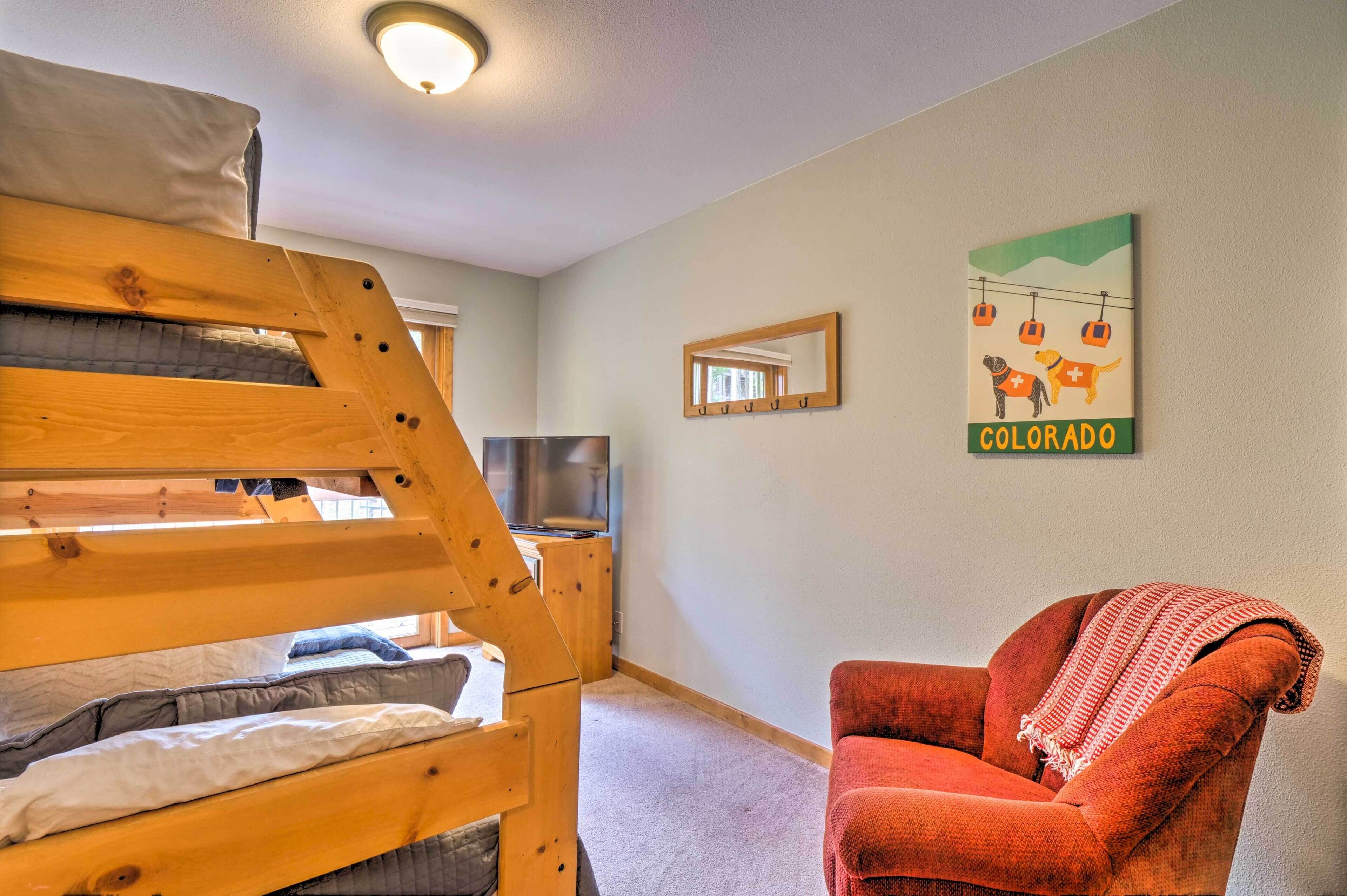 A room with a bunk bed, a television, a red armchair, and a wall with a 'Colorado' sign.
