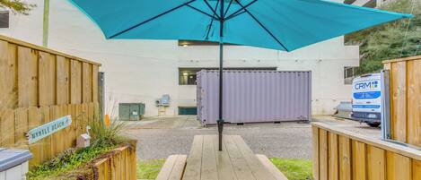A picnic table with a blue umbrella, wooden fences, and a sign that reads 'MYRTLE BEACH.'