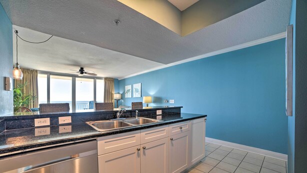 A modern kitchen with a black countertop, stainless steel appliances, and white cabinets. - Spectacular Oceanfront Emerald Beach Resort Condo (Panama City Beach)