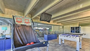 A basketball court with a net, a foosball table, and a seating area with a basketball hoop. - Spectacular Oceanfront Emerald Beach Resort Condo (Panama City Beach)