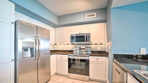 A kitchen with white cabinets, stainless steel appliances, and a granite countertop. - Spectacular Oceanfront Emerald Beach Resort Condo (Panama City Beach)