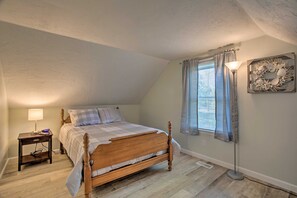Una camera da letto con un letto di legno, un comodino con una lampada, una finestra con tende e una decorazione a parete.