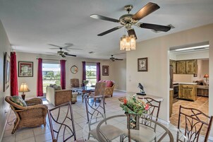 A spacious living room with a dining area, a kitchen, and a ceiling fan.