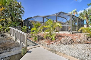 A modern building with a glass structure, surrounded by a wooden deck and palm trees.