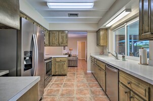 A modern kitchen with stainless steel appliances, wooden cabinets, and a large window providing natural light.