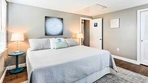 A bedroom with a large bed, two bedside lamps, a decorative wall piece, and a door with a light switch. - Fantastic Plymouth House w/ Deck & Ocean Views! (Plymouth)