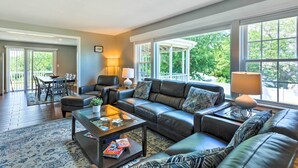 A spacious living room with a leather sofa, a glass coffee table, and a dining area with a table and chairs. - Fantastic Plymouth House w/ Deck & Ocean Views! (Plymouth)