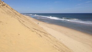 A beach with a sandy slope and a small green umbrella. - Great for Couples! Cape Cod Cottage 2 Mi to Beach (Wellfleet)