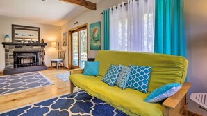 A cozy living room with a yellow sofa, patterned rugs, a fireplace, and a dining area. - Great for Couples! Cape Cod Cottage 2 Mi to Beach (Wellfleet)