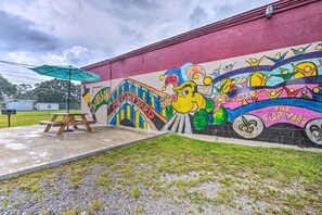 A colorful mural on a building wall with a picnic table and umbrella. - 'the Float Yard' Pensacola Home w/ Pool Table (Pensacola)