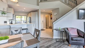 A spacious living area with a dining table, a sofa, and a staircase leading to an upper level.