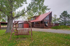 Une cabane rustique en rondins de bois, dotée d’un porche et d’une balançoire.