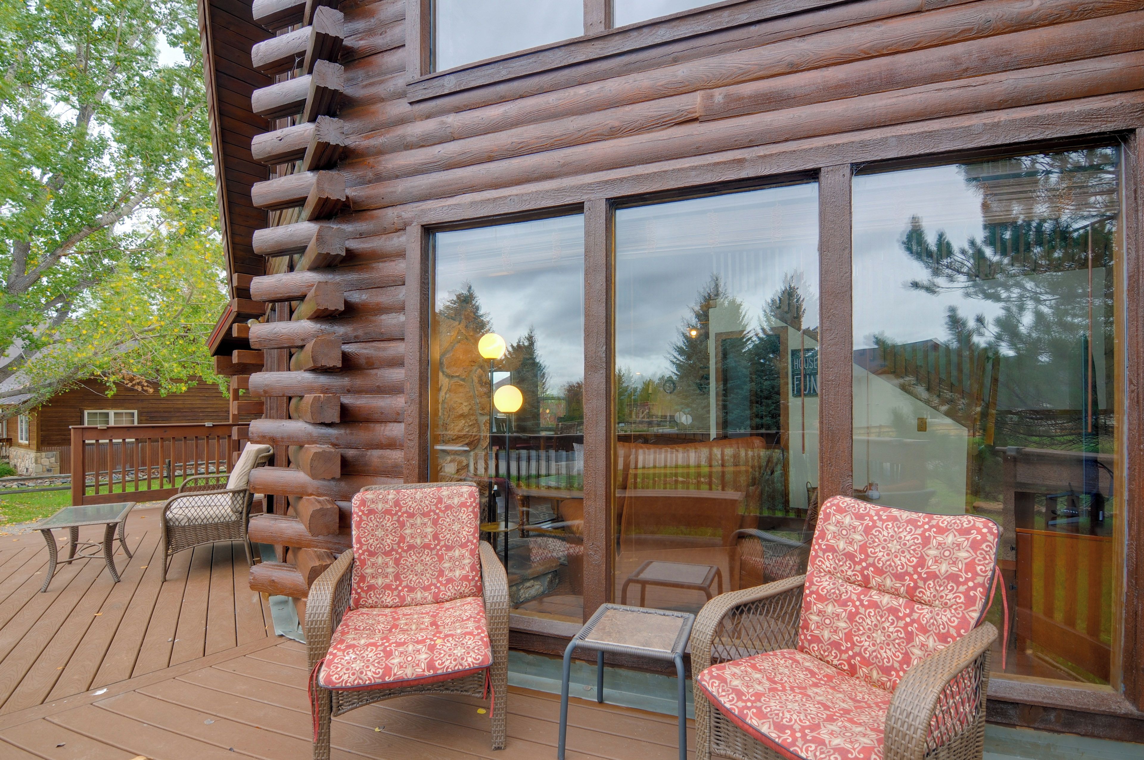 A log cabin with a deck featuring wicker chairs and a table.