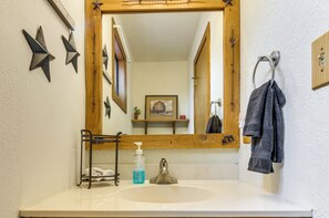 Une salle de bain équipée d’un lavabo, d’un miroir, d’un porte-serviettes et d’éléments décoratifs en forme d’étoiles fixés au mur.