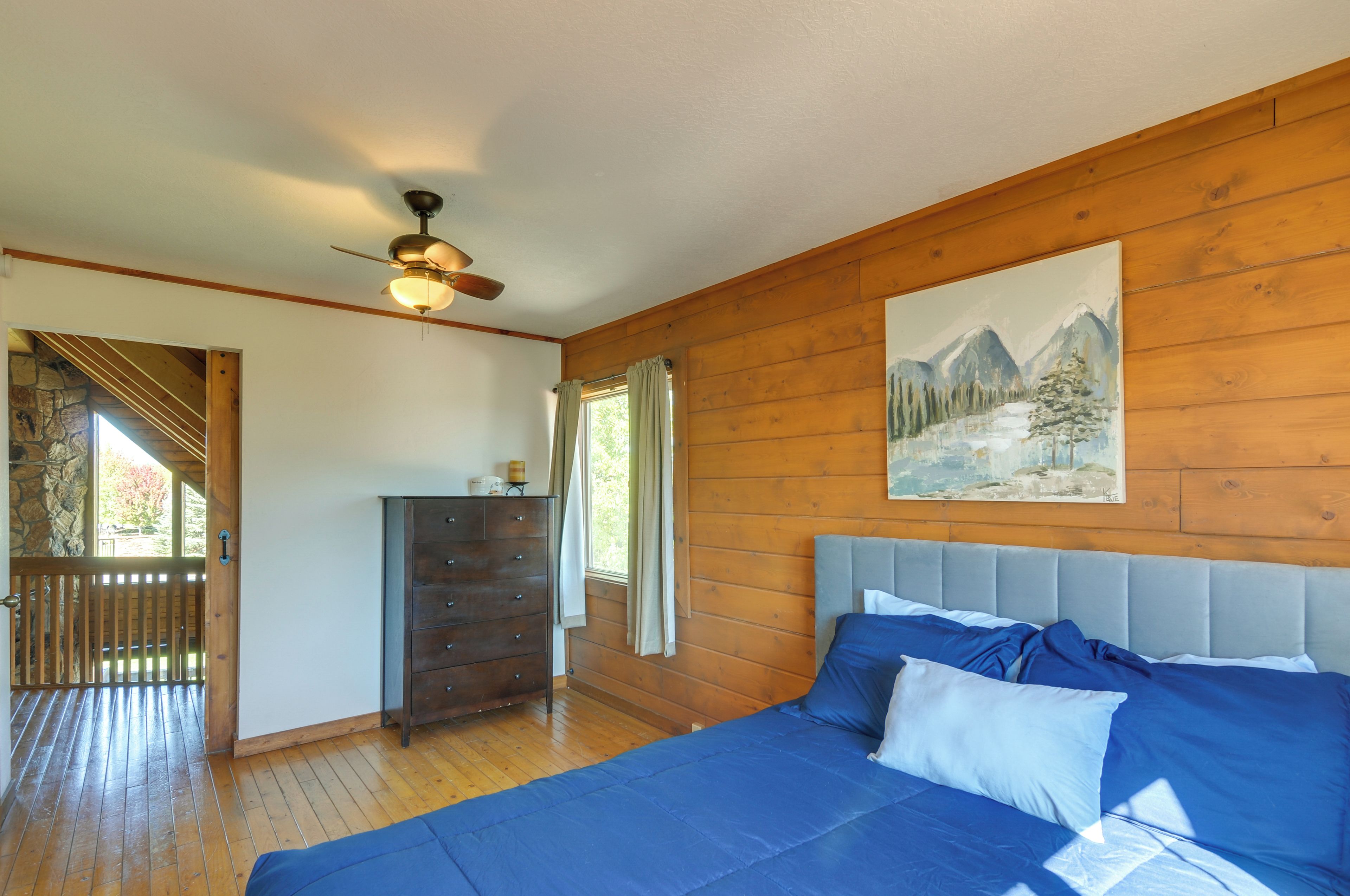 Un dormitorio con una cama, cómoda y un cuadro en la pared.